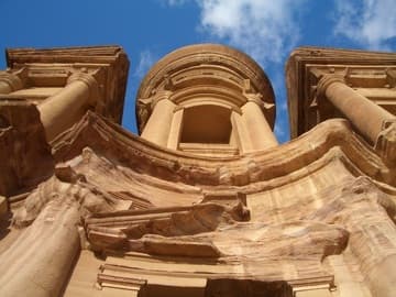 Upper facade of Petra's Monastery against a bright Jordanian sky.