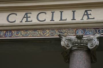 Portico detail with capital, border mosaic, and the Latin name of the patron saint,