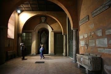 The narthex, with ancient sarcophagus and fragments displayed on the walls. The famous 5th-century door is on the right.