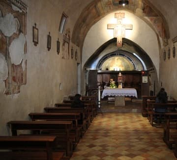 Nave of the ancient church, with frescoes and replica of the crucifix.