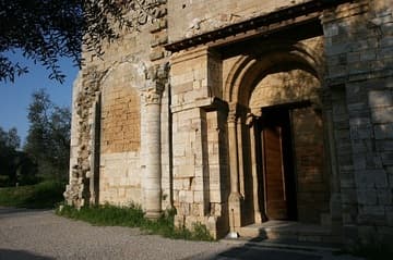 West facade of the Abbey of Sant'Antimo in Tuscany, with 10th-century architrave over the portal, lion capital, and masonry scars from a lost portico. Said to have been founded by Charlemagne in 781, the present abbey church dates from 1118.