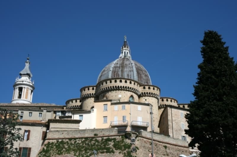 View of the Basilica of the Holy House from the south. Begun in the 15th century, the basilica incorporates a 14th-century castle at its east end. The dome dates from the 1500; the campanile from 1751.