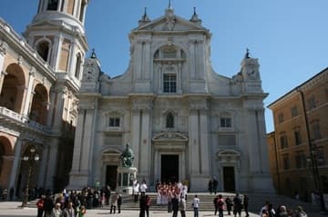 Renaissance facade (1583) of the Basilica della Santa Casa (Basilica of the Holy House) in Loreto, framed by the archway leading into the plaza.