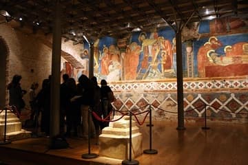 Visitors gather for a guided tour of the "crypt" of Siena Cathedral, built and frescoed in the 13th century. It was abandoned in the early 14th century and not rediscovered until 1999. The frescoes seen here, painted c.1270-80, depict the Crucifixion, Deposition from the Cross, and the Entombment.