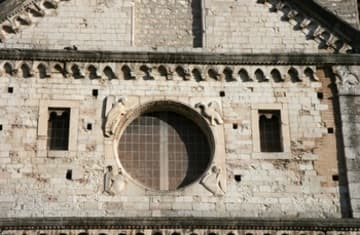 Detail of facade with central oculus and sculptures.