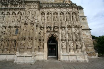 The magnificent west front of Exeter Cathedral is covered with a Decorated Gothic image screen, which was begun in the 1340s and completed nearly a century later. It features three tiers of very weathered sculptures, which include the rulers Alfred, Athelstand, Canute, Willliam the Conqueror and Richard II, as well as saints. The images were originally brightly painted.