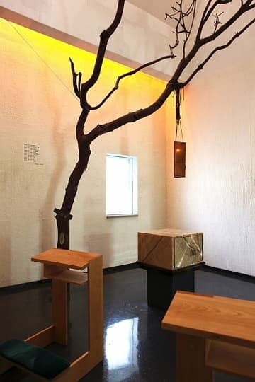 Nestled in the northwest corner of the building, the Blessed Sacrament Chapel is an intimate space bathed in soft orange light. The white walls are coated in beeswax and decorated with gold-leaf prayers of Catholic saints. The focal point of the furnishings is a living Madrona tree that reaches upward to the light, symbolizing the struggle of life. From one of its strong branches hangs a lamp made of amber glass embedded with leaves and seeds. The Blessed Sacrament (bread for the Eucharist) is stored in an onyx box in the center of the room. The opaque glass window in the north wall, which bears the seal of the Jesuits, was designed by Steven Holl himself. Chapel of St. Ignatius (1997) by Steven Holl. Seattle University, Seattle, Washington, USA.