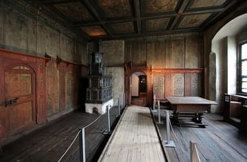The Luther family living room, where the conversations recorded by students in "Table Talk" (starting in 1531) took place. The only woman allowed here was Luther's wife, Katherine von Bora. It was not until around 1535 that Luther could afford to decorate the living room with the painted walls and stove. When Luther's house was sold to the university in 1564, all the rooms were renovated except this one. It has been shown to visitors as a museum ever since. The stove was restored and the ceiling was painted in 1602.