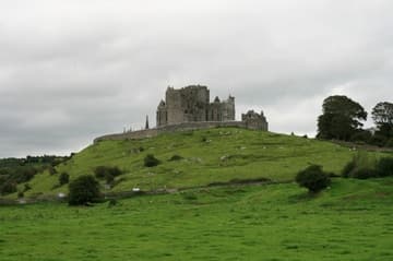 View of the Rock of Cashel from the west, near Hore Abbey. The rock is dominated by the 13th-century cathedral, with a fortified tower-house added to the west end in the 15th century. Rock of Cashel, County Tipperary, Ireland.