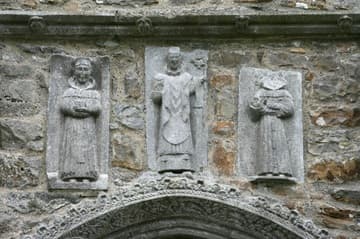Sculptures of Saints Dominic, Patrick and Francis above the north door of the cathedral, added in the 1450s. An inscription above the door attributes this and other improvements to Odo, dean of Clonmacnoise, who died in 1461. Clonmacnoise, Ireland.