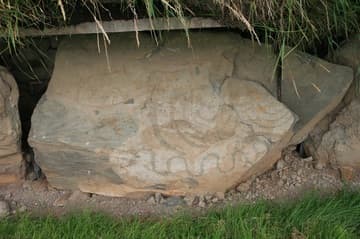 Decorated kerbstone with spiral and serpent motifs.