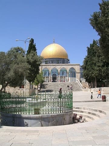 In the foreground, the green-fenced El-Kas Fountain where Muslims perform ritual ablutions before entering the holy sites. Beyond the fountain is the stairway leading through the south qanatir (colonnade) to the Dome of the Rock.