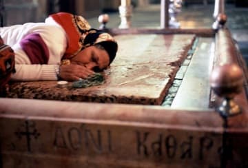 A woman prays at the stone of unction.