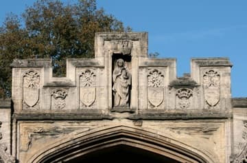 Weathered sculpture of St Mary Magdalene on the gate leading into St John's Quad. Magadalen College, Oxford, England.
