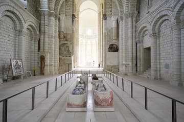Nave of the Romanesque abbey church (1105-60), looking east. The polychrome tombs in the foreground are those of King Henry II Plantagenet (d. 1189); Eleanor of Aquitaine (d. 1204), Henry's queen; King Richard I the Lionheart (d. 1199), their son; and Isabella of Angouleme (d. 1246), the wife of their youngest son, King John (d. 1216). Abbey of Fontevraud, Loire Valley, France.