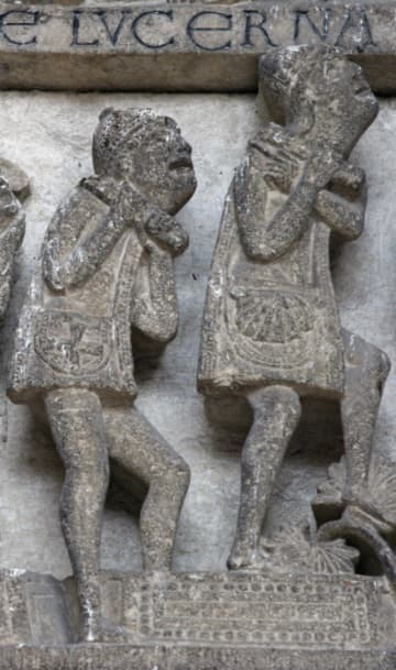 Detail of the Last Judgment tympanum over the west door, sculpted by Gislebertus around 1130. Here on the lower left, the redeemed rise from their graves and rejoice with an angel. On the right can be seen two pilgrims with symbols on their bags - a Greek cross indicating Jerusalem and a scallop shell representing Santiago de Compostela. On the left, a person sits on his grave and unwraps his grave clothes, looking up in wonder.
