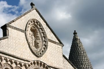 Top of west facade and conical roof of the right tower, both mid-12th-century, Notre-Dame-la-Grande, Poitiers. The mandorla at top center depicts Christ in Majesty. Both the richly sculpted facade and pinecone tower are characteristics of Romanesque churches in the Poitou region.