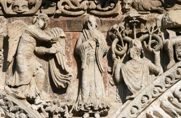The Annunciation and the Stem of Jesse (representing the royal family tree of Jesus). Traces of blue paint can be seen on the robes of the Archangel Michael and Virgin Mary. The faces have been smashed by iconoclasts. Detail of 12th-century west facade of &Eacute;glise Notre-Dame-la-Grande, Poitiers.