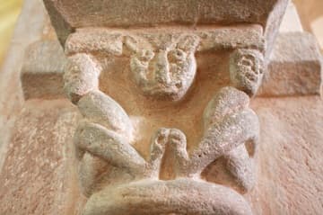 Two human-like figures who may be acrobats, with a lion's face between them. Romanesque capital, 12th century. Gourdon Church, Burgundy, France.