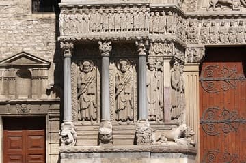 The redeemed march to heaven on the lintel, while saints and lions stand guard below. From left: Bartholomew, James the Greater, Trophime, John, Peter. Detail of Romanesque portal, 12th century. Eglise St-Trophime, Arles, France.