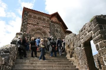Visitors admire the 12th-century portal at the top of the stairs.