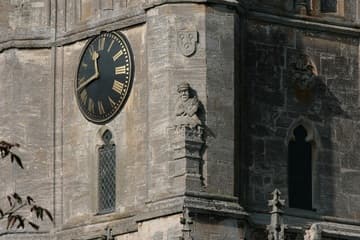 The central tower is the only significant survival from the previous church. The bottom section, up to the clock, was built by the Earl of Warwick in the early 15th century in a Decorated Gothic style. The upper part was added by John Tame in the late 15th century, in the Perpendicular Gothic style. Grotesque guardians stand at each corner of the tower beneath stone-carved padlocks; this one is on the southeast corner.