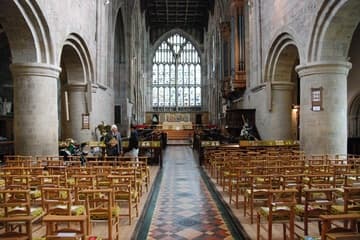 The austere Norman nave, with great cylindrical pillars, undecorated capitals, and plain walls, leads to the light and airy Perpendicular Gothic chancel in the east end.
