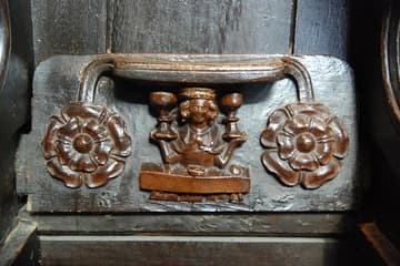 Misericord depicting one of the Labors of the Months. This is January, with a finely dressed man sitting at table and holding two chalices. The chalices represent the duality of the old year and the new year.
