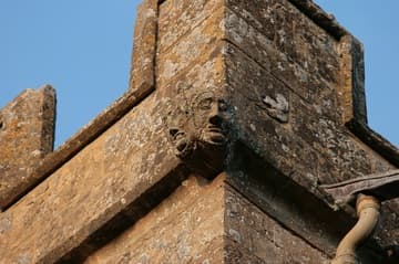 Two-faced corbel head on the tower.