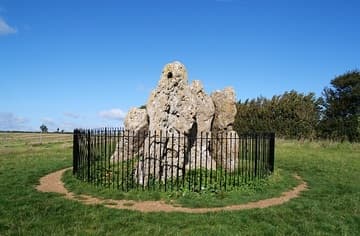 The Whispering Knights, a tight cluster of four stones; a fifth, probably the capstone, has fallen. The stones are part of a portal dolmen-type burial chamber dating from about 4000-3500 BC, and originally projected out of a low, flat-topped platform that surrounded them. Dismembered bodies were placed in the chamber for burial. Human remains were place in the chamber for over a thousand years, well into the Bronze Age. The Whispering Knights are named for the conspiratorial way in which they lean in towards each other. Local legend has it that they were plotting against their king when they were turned into stone by a witch, along with the other monuments at Rollright. Another legend says that on New Year's Eve, at the tolling of the bells of Long Compton church, the stones go down to the valley to drink. Rollright Stones, Oxfordshire, England.