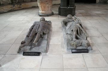 William Marshal Earl of Pembroke (d.1219) and an unknown knight. Two of ten knightly memorials in the round nave of the Temple Church, London. These were believed to be tombs until the post-WWII restoration revealed no bodies, but only effigy memorials. All the knights are on their back, but are otherwise positioned in different ways: some have their legs extended straight out while others have their legs crossed; some wear tunics over their armor and others wear full-length robes; some clutch their swords, some pray, and some have their arms straight at their sides. One has no effigy at all, but only a trapezoidal sarcophagus lid.