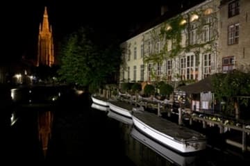 The soaring spire of the Church of Our Lady reflected in a Bruges canal.
