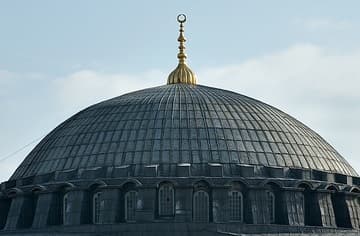 A closeup view of Hagia Sophia's magnificent dome, which rises 184 feet (56m) in height (about 15 stories) and spans a width of approximately 102 feet (31m). The diameter of Hagia Sophia's dome is just slightly smaller than that of the Pantheon in Rome. Below the dome is a crown formed by 40 windows and ribs, through which light filters into the glittering with the gold interior of the dome.