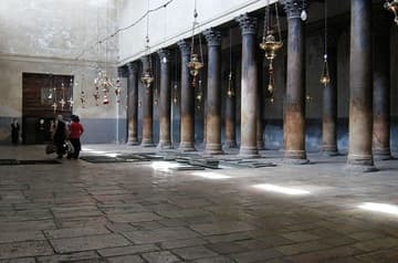 Interior of the Church of the Nativity, looking west down the nave. The trapdoors in the floor reveal 4th-century floor mosaics from the Constantinian church.