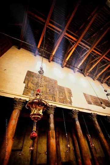 Chandelier and wall of the ancient nave, with fragments of mosaics.