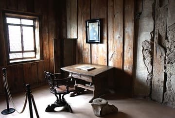 The Luther Room, with a facsimile of the September Testament and portrait of Luther in disguise at Knight George. The whale vertebra is the only original furnishing; Luther used it as a footstool.