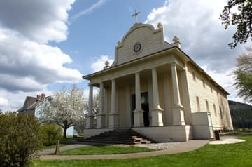 Exterior view of the mission church from northwest. The Sacred Heart Mission near Coeur d'Alene was built 1850-53 by Jesuit missionaries and Native Americans. It is the oldest building in Idaho. Today it is owned by the Coeur d'Alene tribe and operated by the state as Old Mission State Park.