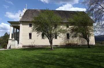 West side of the mission church. The Sacred Heart Mission near Coeur d'Alene was built 1850-53 by Jesuit missionaries and Native Americans. It is the oldest building in Idaho. Today it is owned by the Coeur d'Alene tribe and operated by the state as Old Mission State Park.