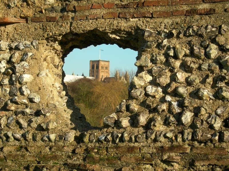 Norman tower of St Albans Cathedral seen through a hole in the Roman wall. Related pages:
