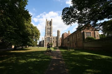 The west front of Ely Cathedral, lopsided due to the loss of its northwest transept. The Romanesque facade was completed in 1189, with the Galilee porch added in 1215 (Early English Gothic) and the top of the west tower added in 1392.