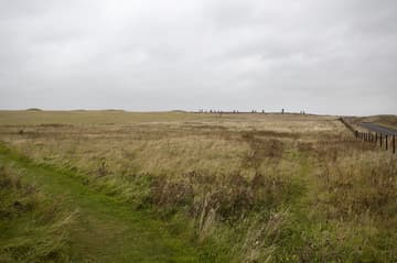 General view from east, with the Comet Stone in the central foreground, the B9055 road on the right, and small burial mounds visible on the left. Ring of Brodgar, c. 2500 BC. Mainland, Orkney Islands, Scotland. Measuring nearly 104 m in diameter, this impressive Neolithic monument is a true circle that is thought to have originally consisted of 60 stones. Today 27 stones remain standing, ranging in height from 2.1 m to 4.7 m. The ring is positioned on a scenic strip of land between the freshwater Loch of Harray (to NE) and the saltwater Loch of Stenness (to SW).