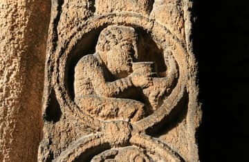 A man drinking from a cup. Detail of the Prior's Door in the south aisle of the nave, a magnificent example of 12th-century Romanesque carving. Dating from about 1150, its tympanum depicts Christ in Majesty held aloft by archangels and blessing the creatures of the universe. Two human heads peer down from the corners and the pillasters on the sides have medallions populated by various beasts and humans.